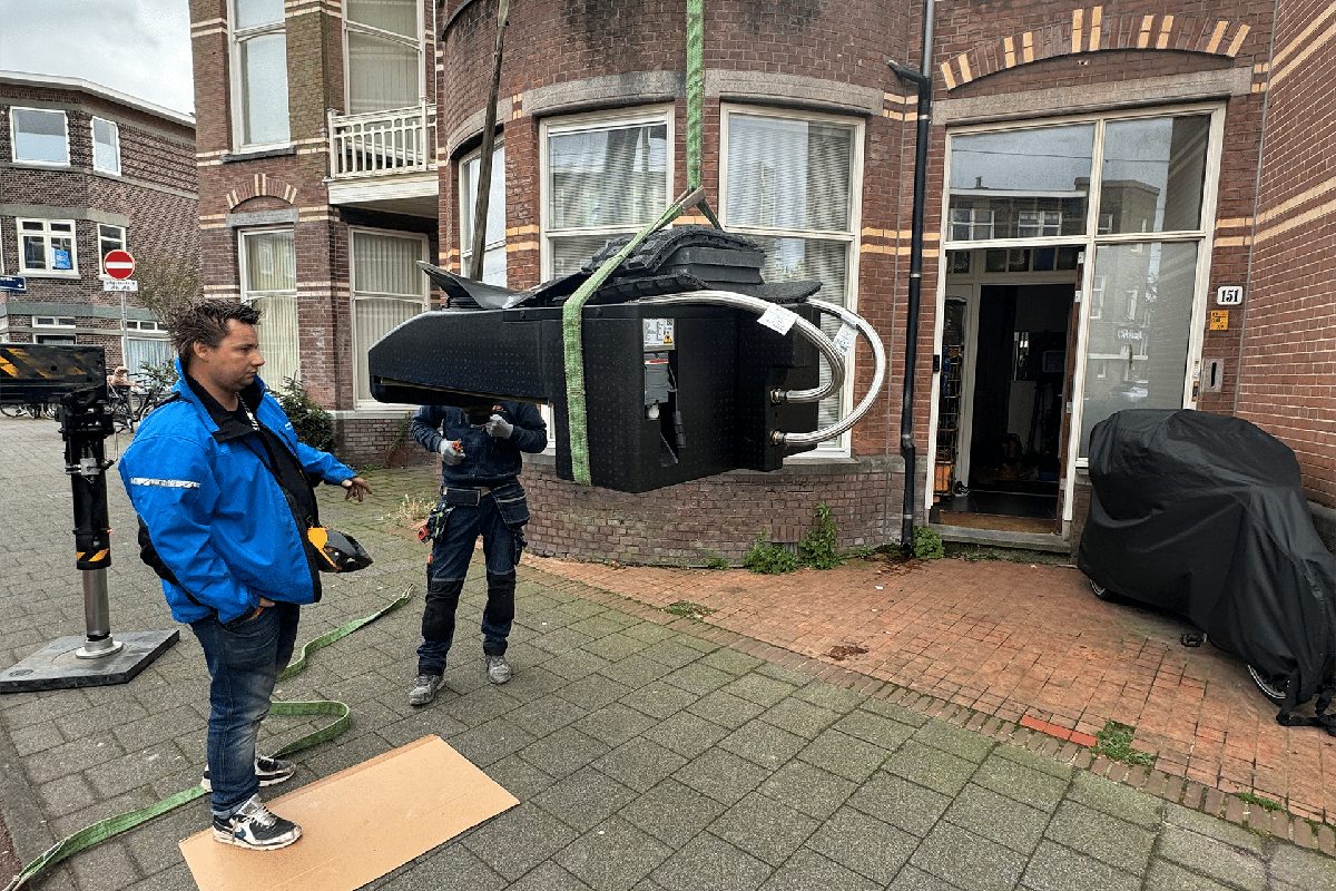 Warmtepomp-unit wordt met een hijsband voor een woning geplaatst