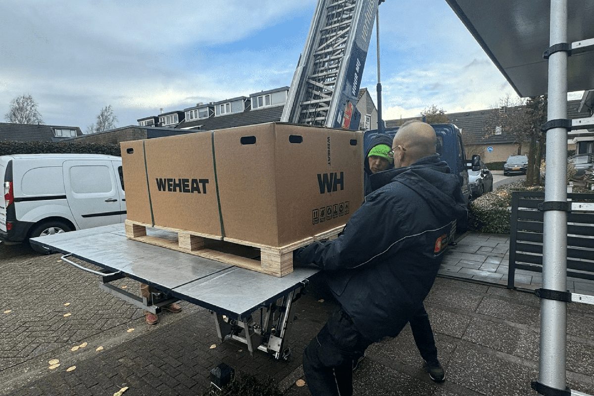 Monteurs laden een WeHeat warmtepomp uit bij een woning